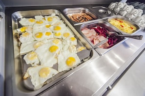 A buffet with fried eggs, sausages, ham, and scrambled eggs. - Hotel Confort (Cluj-Napoca)