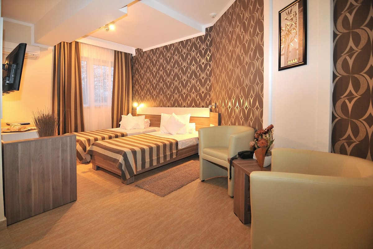 A hotel room with two beds, a desk, a chair, and a TV.