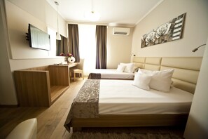 A hotel room with a bed, a desk, a chair, a TV, and a painting on the wall. - Hotel Confort (Cluj-Napoca)
