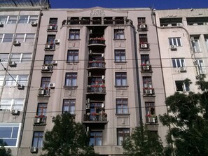 Un hôtel à plusieurs étages doté de balcons, de climatiseurs et d’une entrée principale.