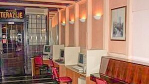 A hotel lobby with a glass partition, wooden paneling, and a seating area with red chairs. - Hotel Kasina (Belgrade)