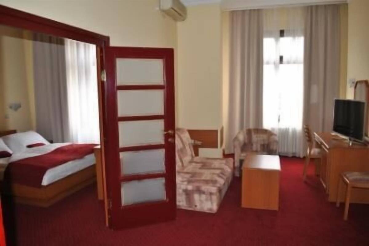 A hotel room with a bed, a sofa, a desk, and a television.