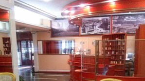 A lobby with a reception desk, a seating area with two armchairs, and a large window with a view of the street. - Hotel Kasina (Belgrade)