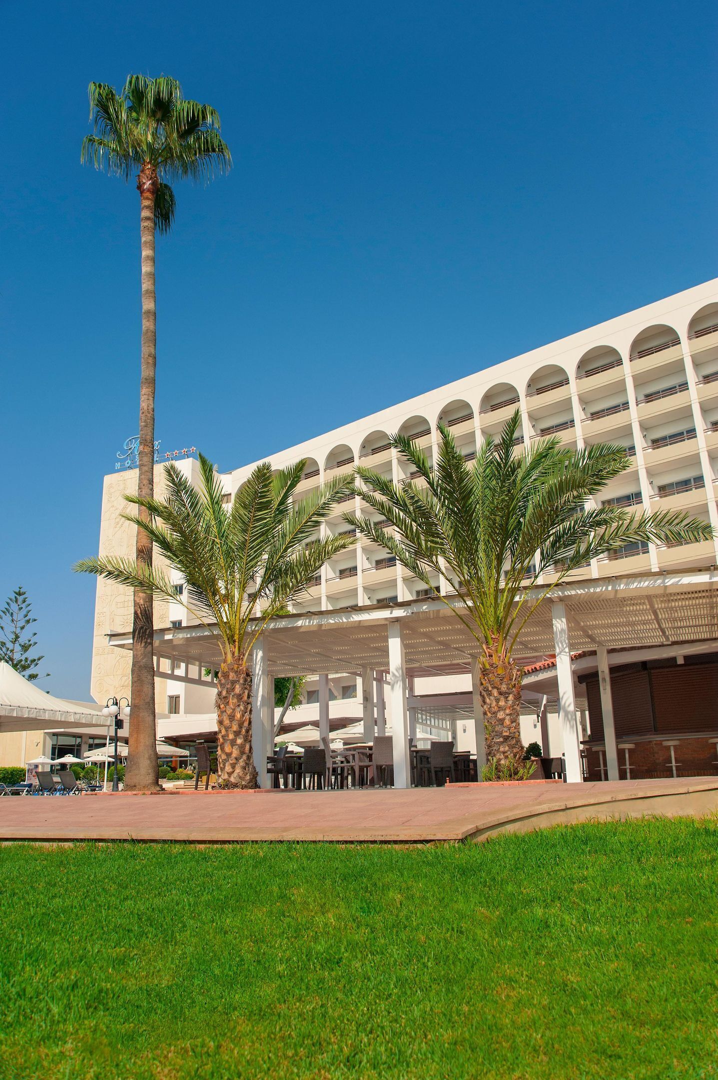 A hotel with a modern architectural design, featuring a central courtyard with palm trees and outdoor seating areas.