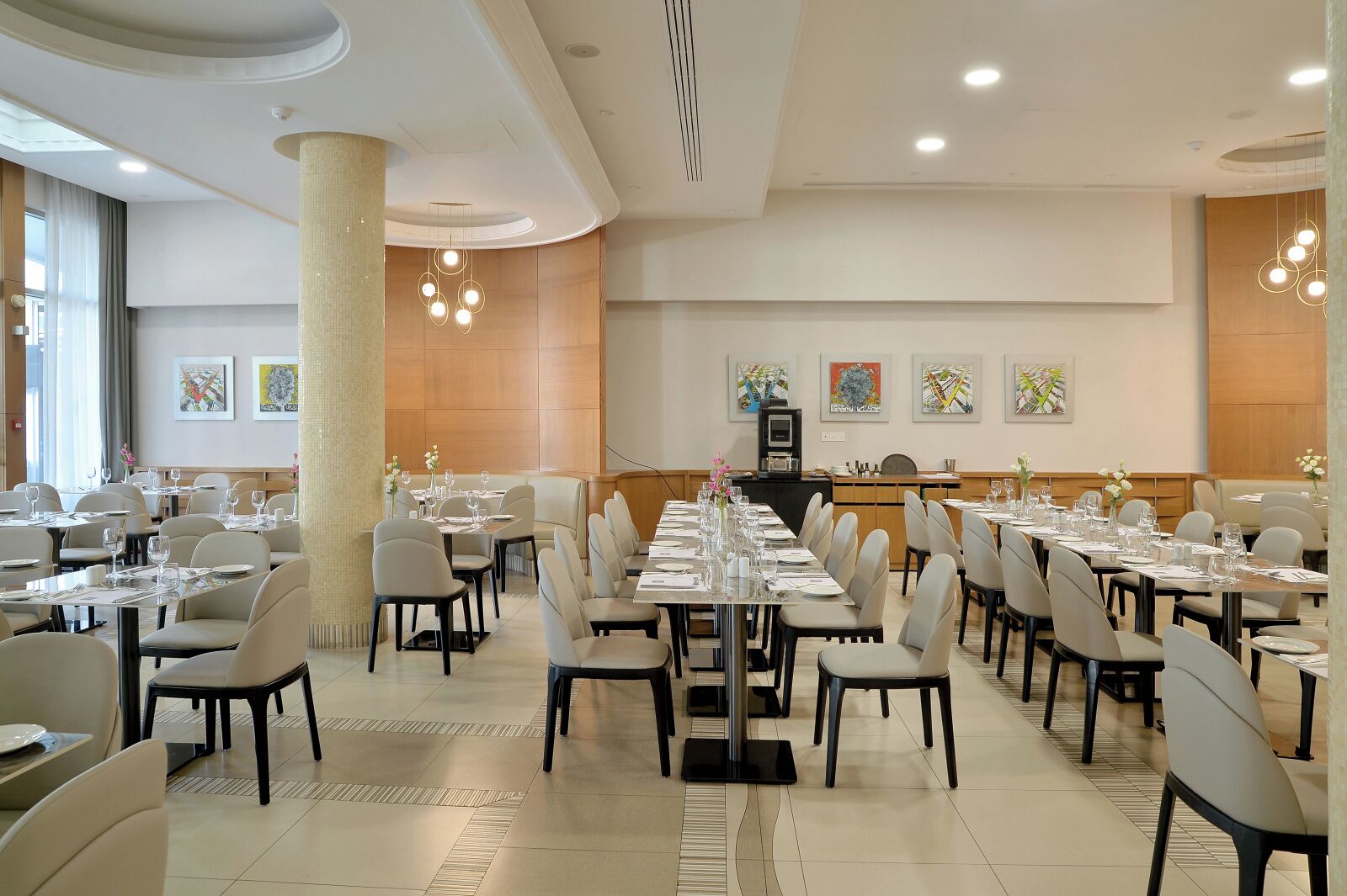A spacious dining area with multiple tables and chairs, a central service counter, and artwork on the walls.