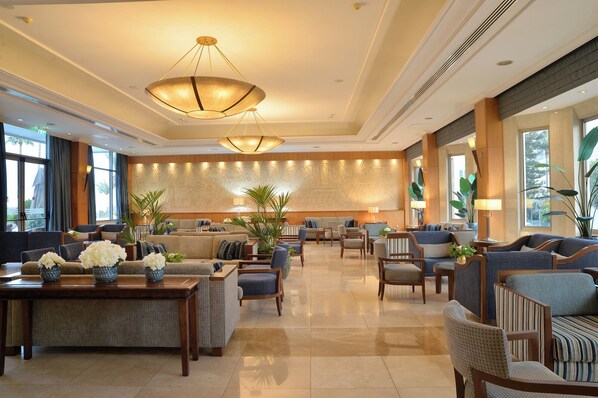 A spacious lobby with a central seating area, large windows, and a decorative wall mural. - Ajax Hotel (Limassol)