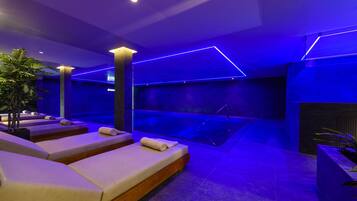 Relax in a serene spa room with massage chairs, a geometric patterned wall, and a calming atmosphere.