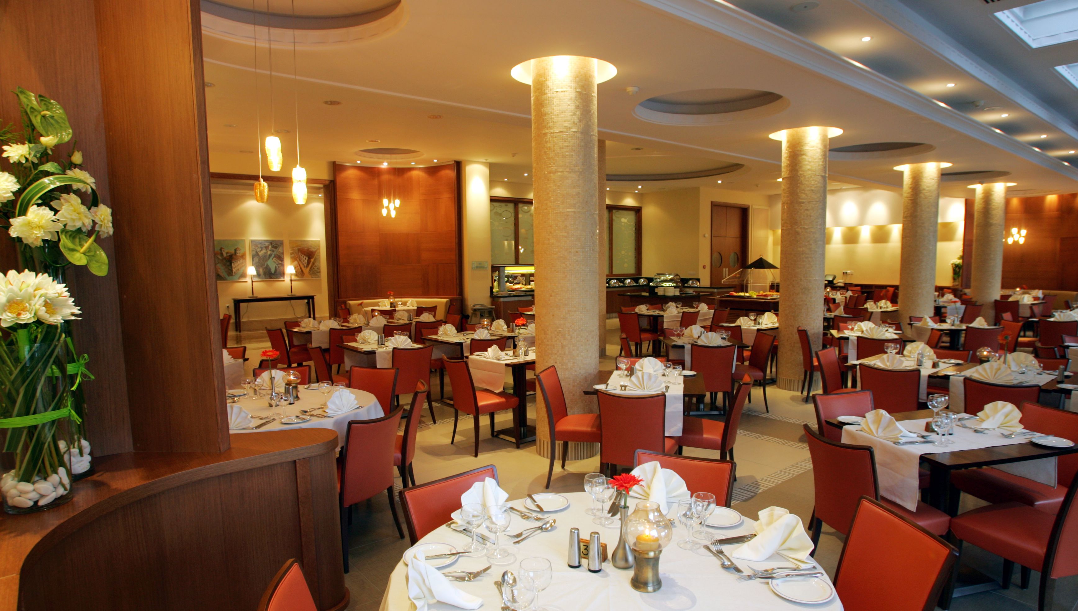 Un restaurant spacieux, doté de nombreuses tables et chaises, de grandes colonnes et d’un intérieur bien éclairé.
