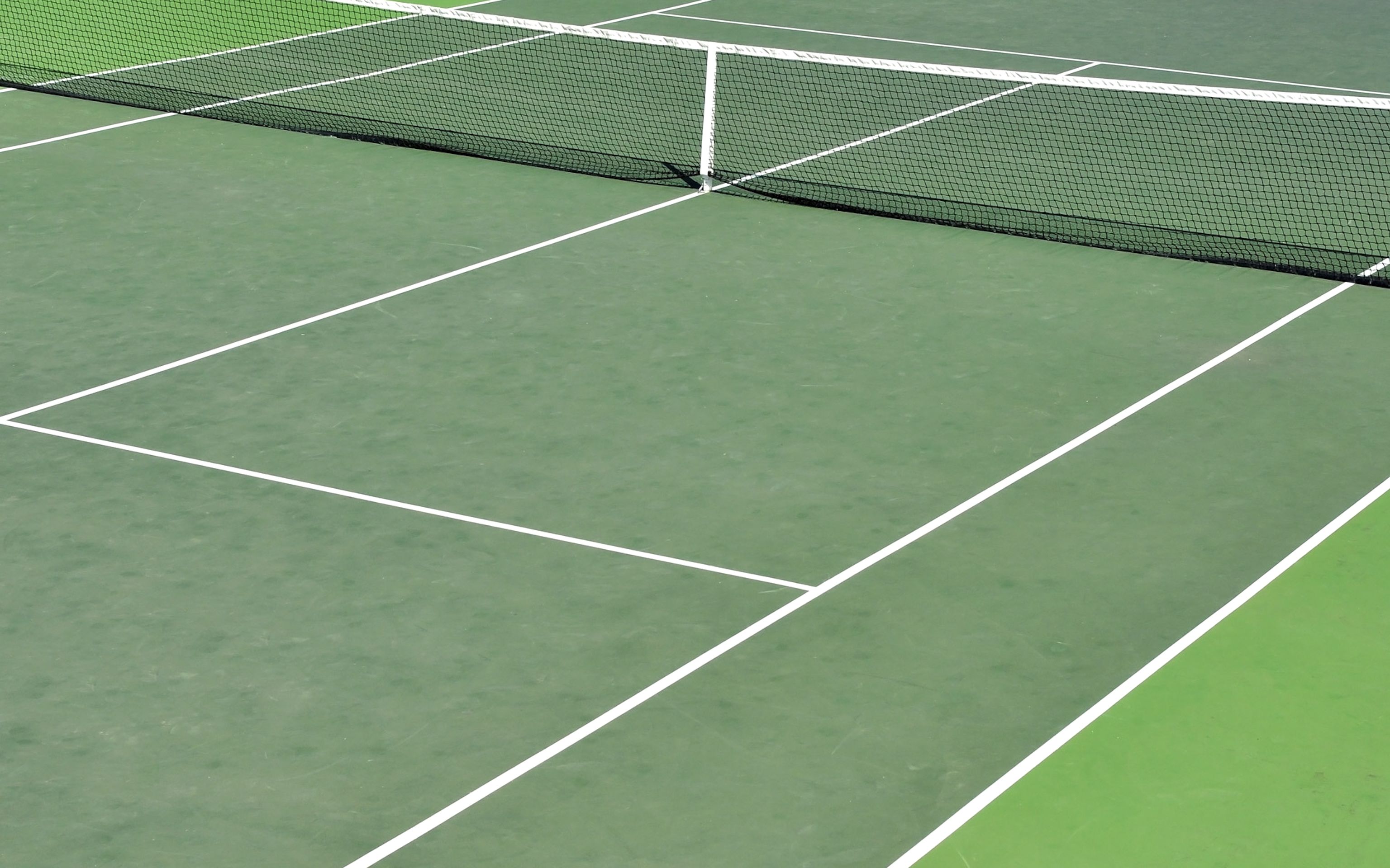 A tennis court with white boundary lines and a net.