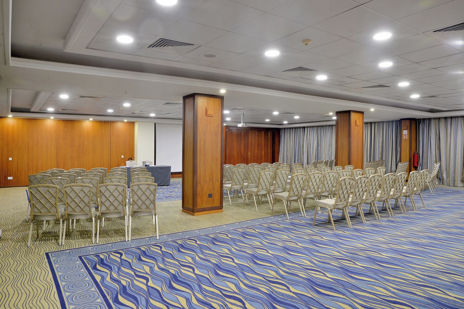 A conference room with rows of chairs, a podium, and a carpeted floor.