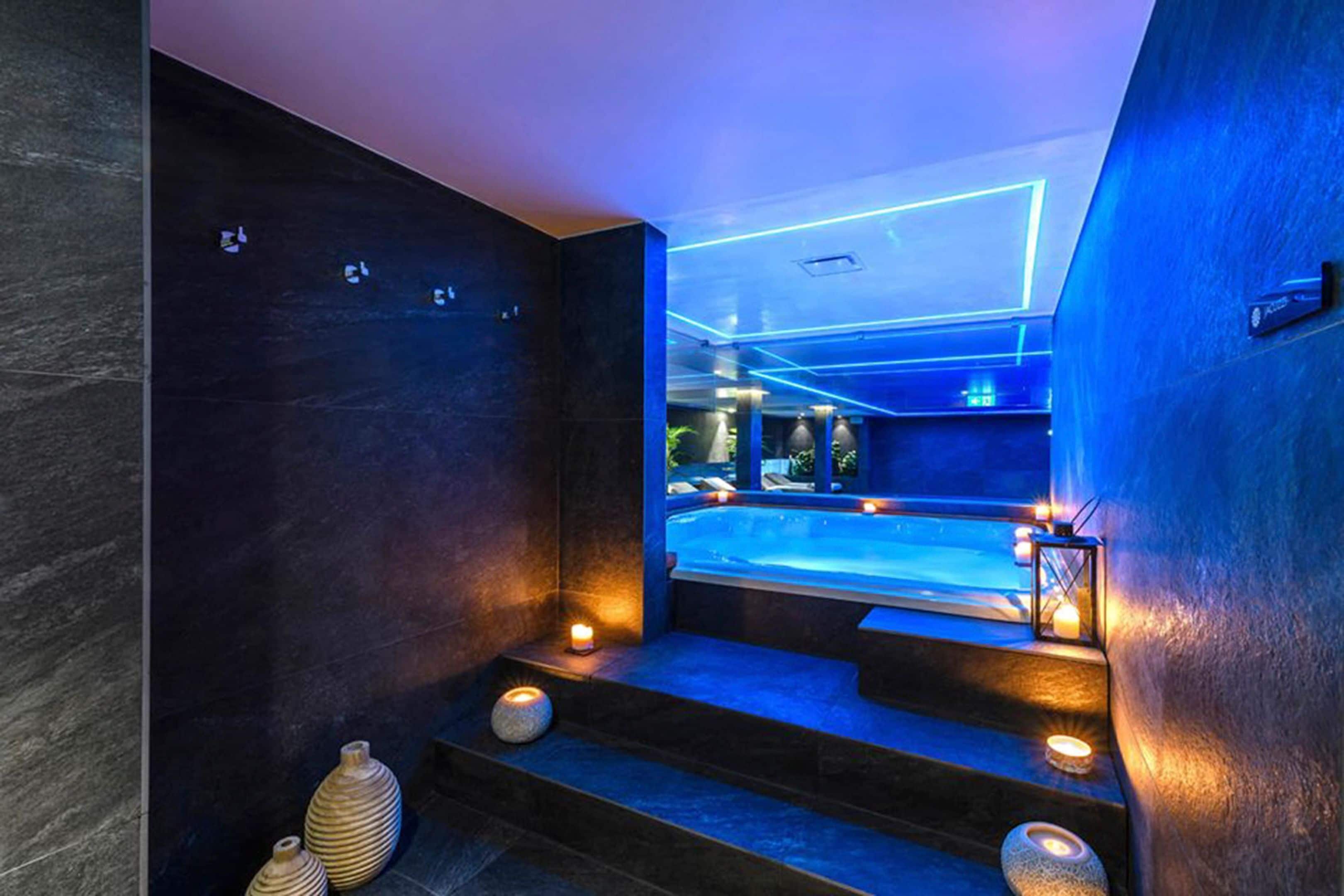 A modern spa area with a hot tub, dim lighting, and stone steps leading to the tub.