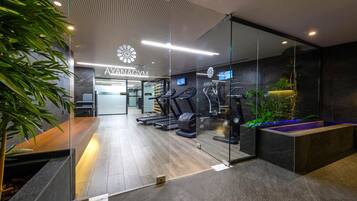 A modern gym with exercise equipment, a reception area, and a glass wall.