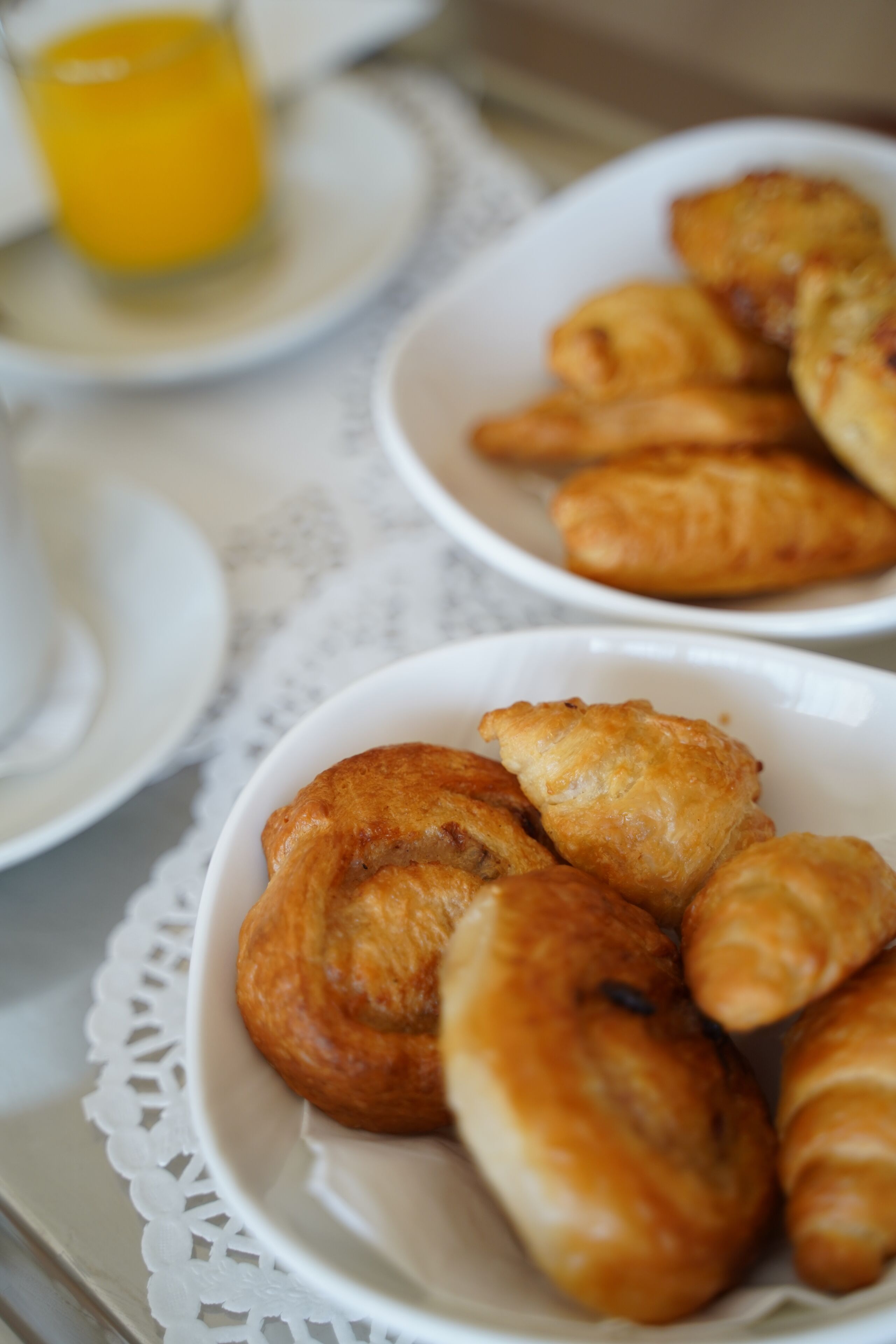 A table with plates of pastries and a glass of orange juice.