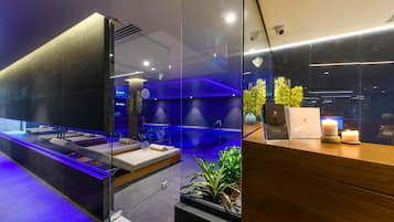 A modern spa area with a glass partition, a reception desk, and a blue-lit wall.
