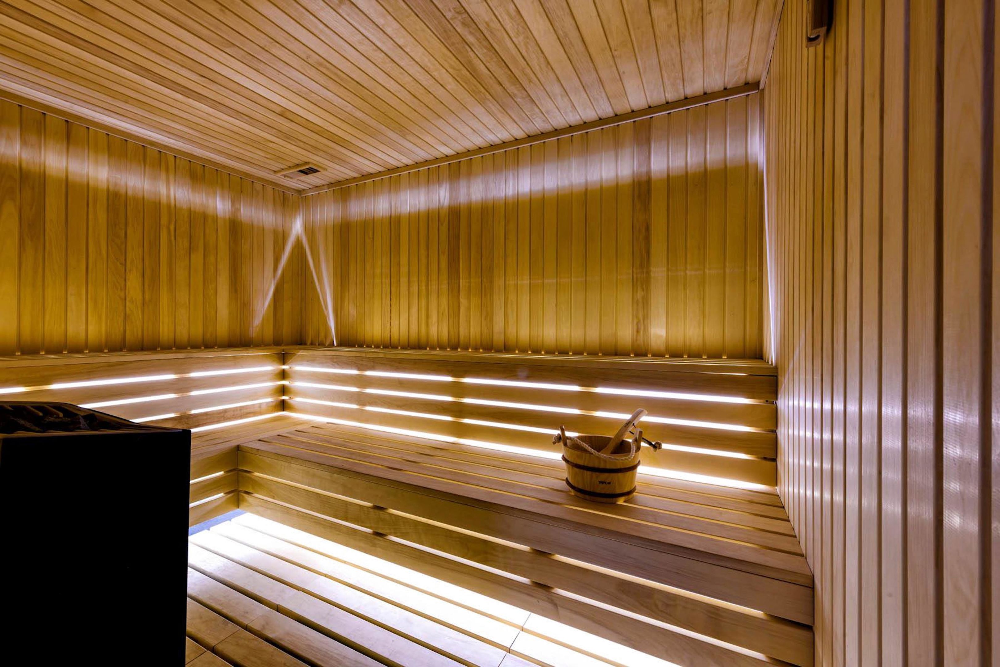 A sauna with wooden benches and a bucket with a brush.
