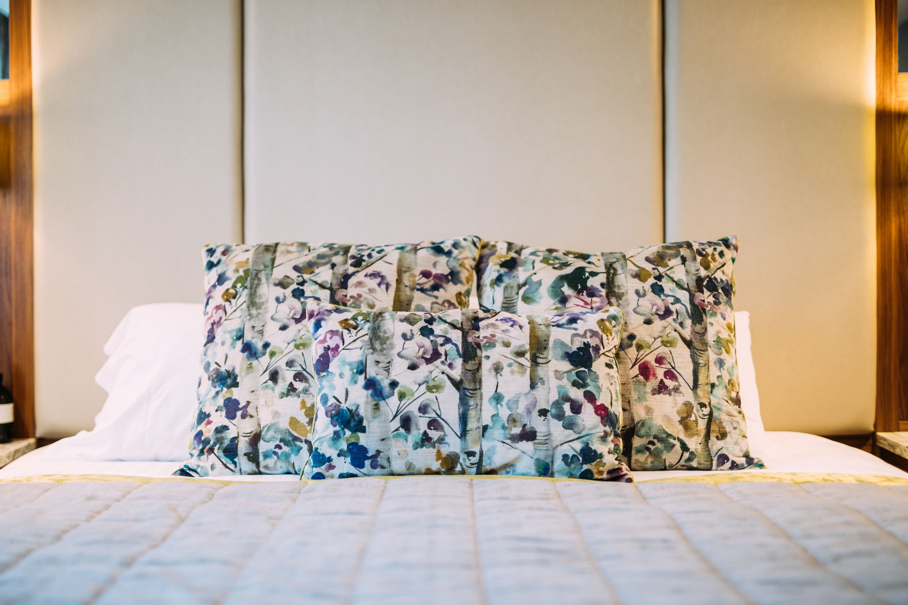 A bed with a floral-patterned pillow and a quilted bedspread.