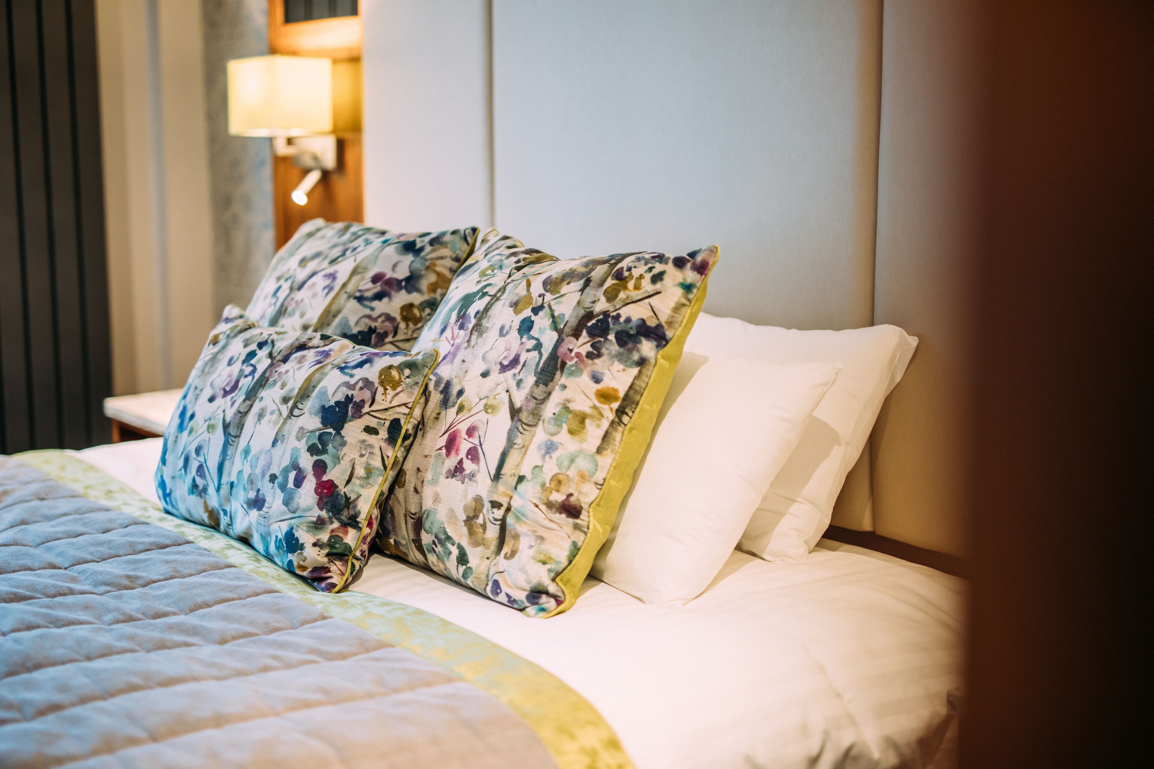 A neatly made bed with floral-patterned pillows and a white comforter.