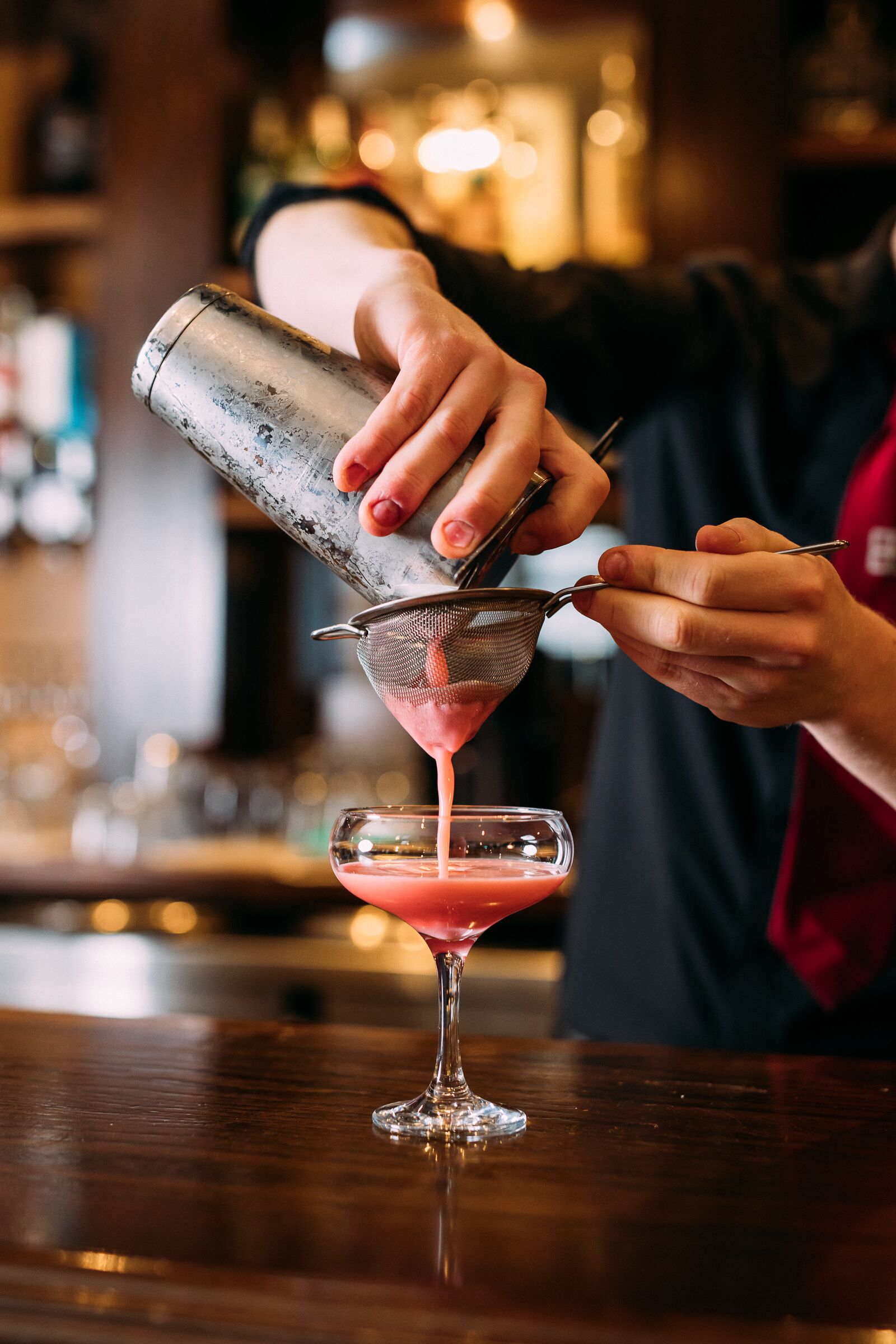 Un barman sirviendo una bebida en una copa de martini.