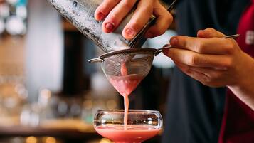 Un barman sirviendo una bebida en una copa de martini.