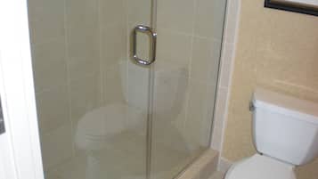 Un baño con ducha corredera de vidrio, inodoro y lavabo.