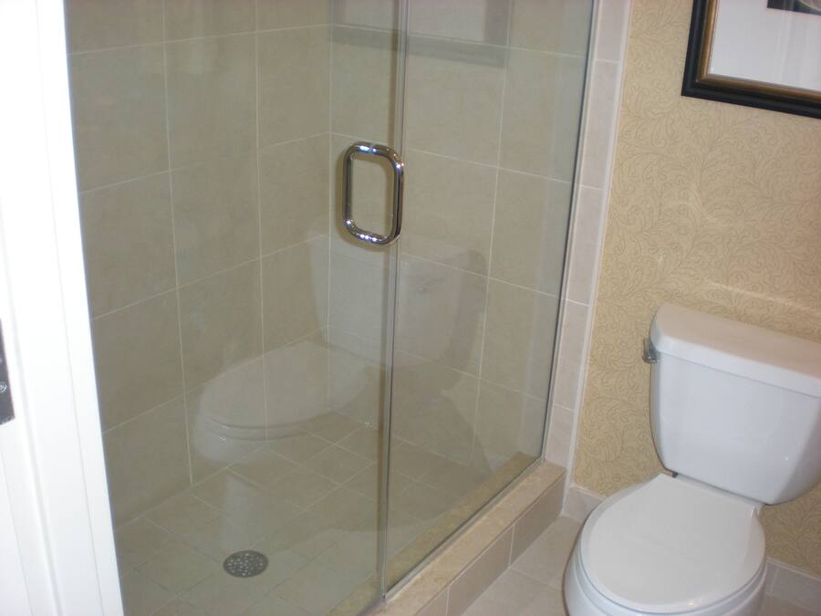 Un baño con ducha corredera de vidrio, inodoro y lavabo.