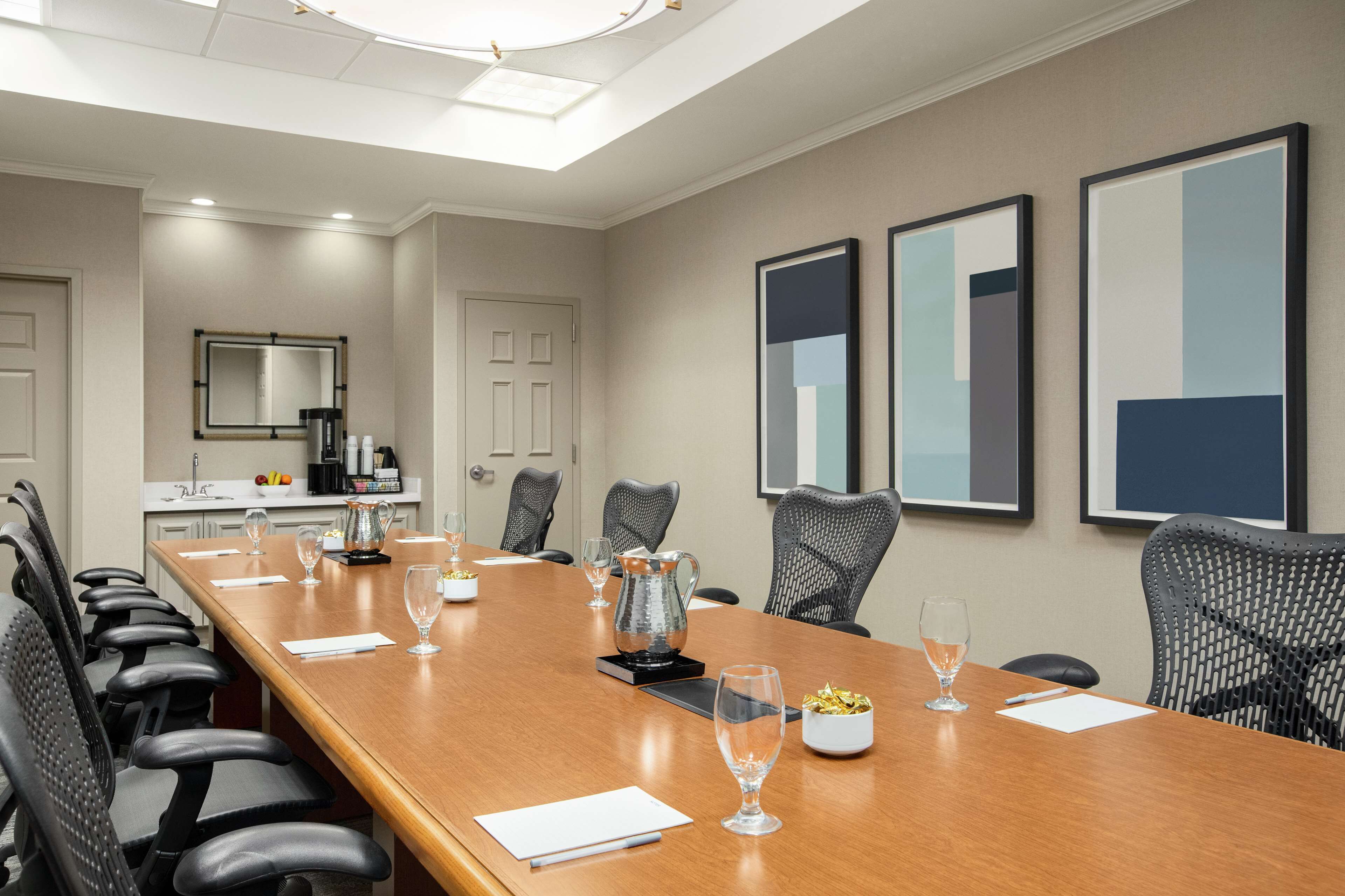 A conference room with a long table, multiple chairs, and a coffee station.