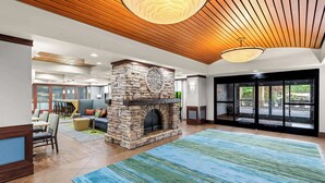 A spacious lobby with a stone fireplace, wooden ceiling, and large windows offering a view of the outdoors. - Hampton Inn Chattanooga - North/Ooltewah (Ooltewah)