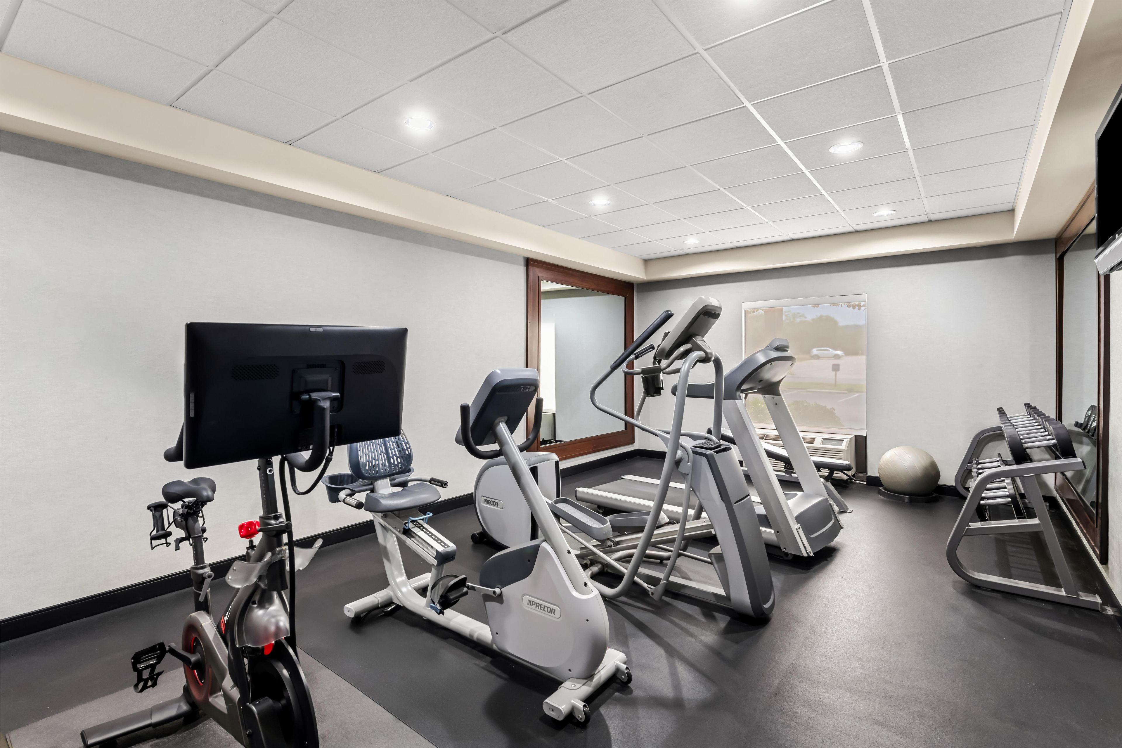 Un gimnasio con cintas de correr, elíptica, bicicleta estática y máquina de remo.