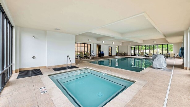 A large indoor swimming pool with a tiled floor, a diving board, and lounge chairs. - Hampton Inn Chattanooga - North/Ooltewah (Ooltewah)