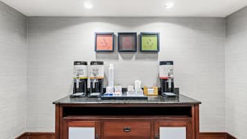 A coffee station with two coffee dispensers, a water cooler, and a small tray with cups and utensils.