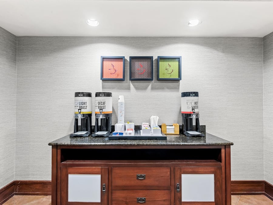 A coffee station with two coffee dispensers, a water cooler, and a small tray with cups and utensils.