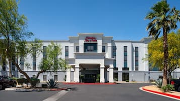 Welcome to Hampton Inn & Suites, featuring a grand entrance with columns and beautifully landscaped surroundings.