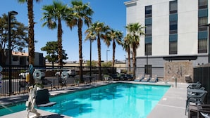 A swimming pool with lounge chairs and palm trees. - Hampton Inn & Suites Las Vegas Airport (Las Vegas)