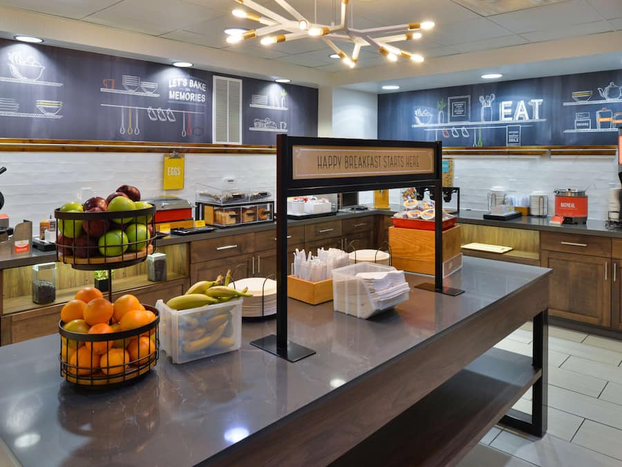 Zona de desayuno tipo buffet con diversas frutas y productos para el desayuno.