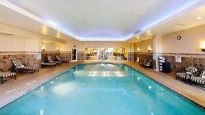 Una piscina interior con sillones de descanso y una recepción al fondo.