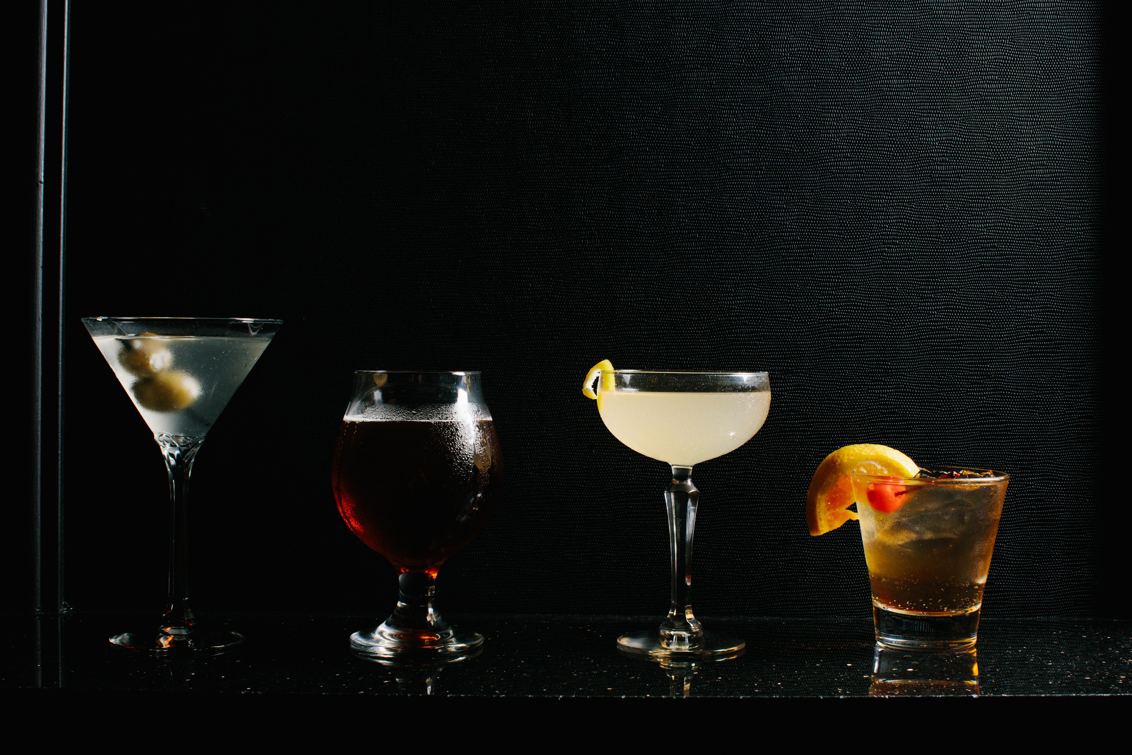 Four different types of drinks in various glasses.