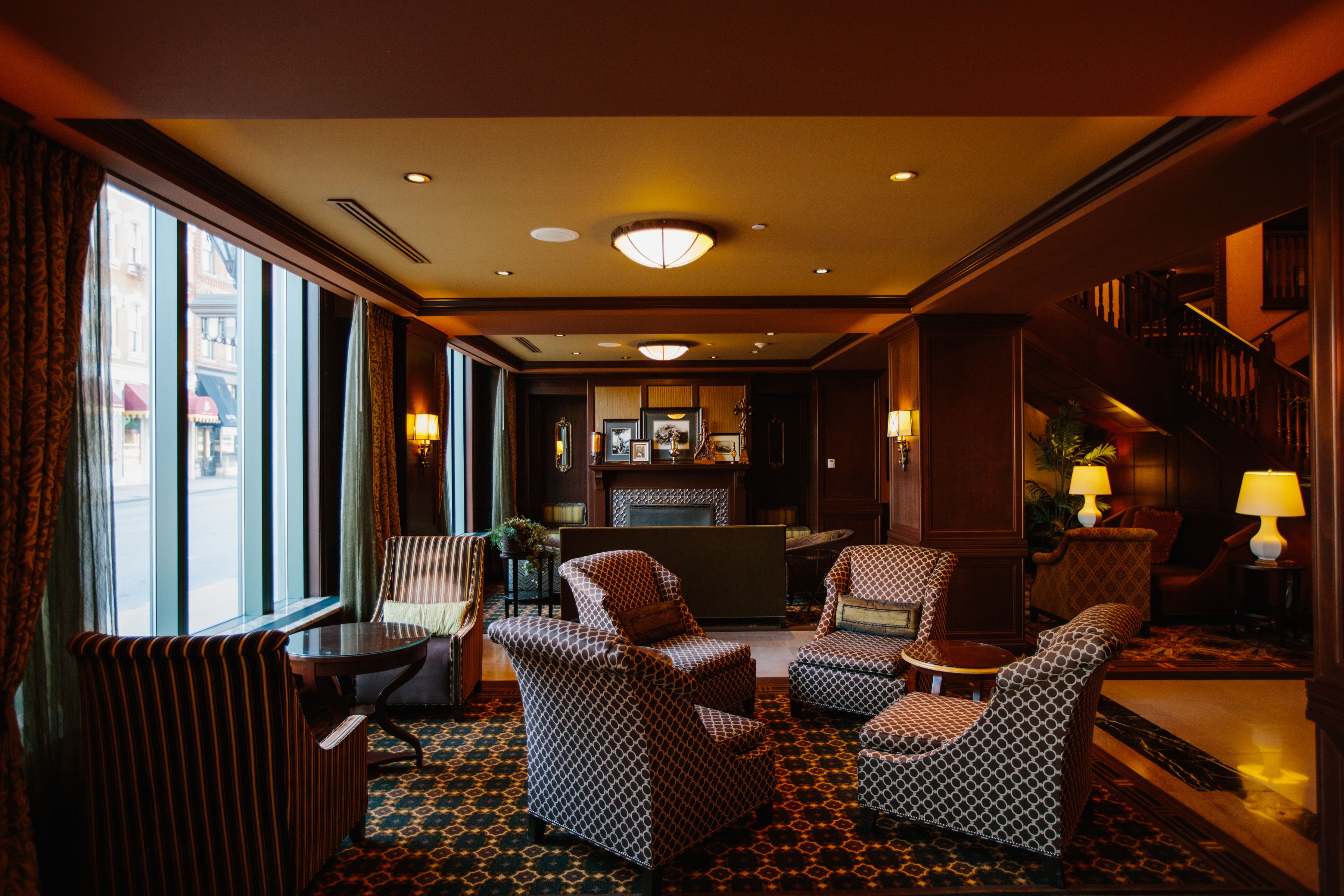 A hotel lobby with patterned armchairs, a reception desk, and a staircase.