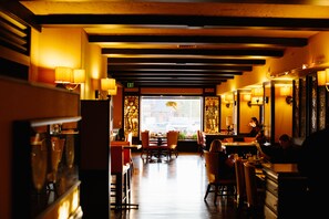 Un restaurante con mesas y sillas, un letrero de salida y vistas a la calle.