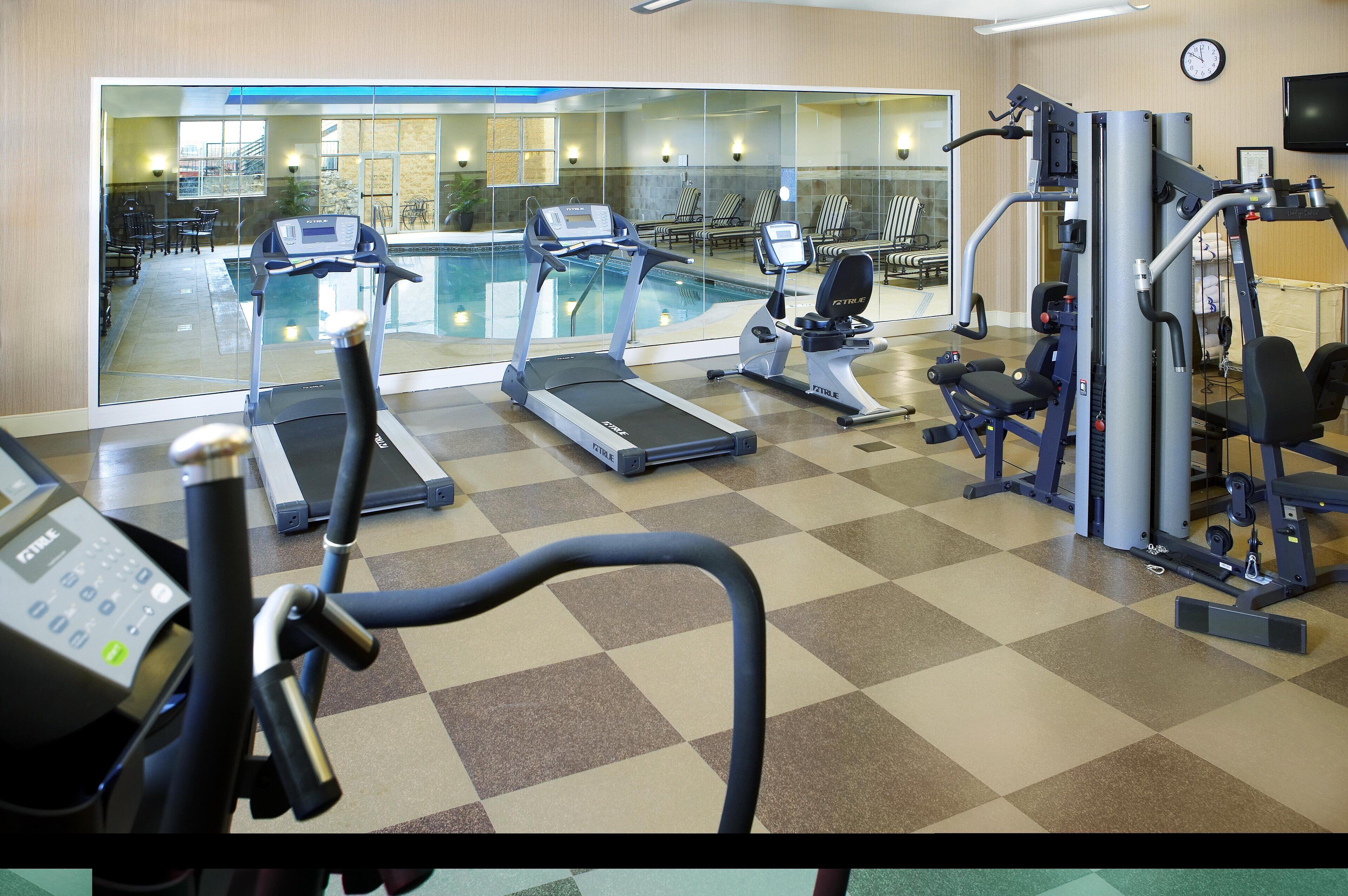 A gym with treadmills, a rowing machine, and a weight bench.
