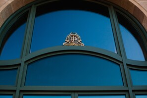 Fachada de edificio con un gran ventanal arqueado y un emblema de escudo.