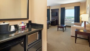 Une chambre d’hôtel équipée d’une kitchenette, d’un téléviseur à écran plat, d’un canapé, d’une table basse et offrant une vue sur la ville.