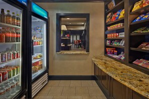 A hotel corridor with a refrigerated beverage display, snack shelves, and a marble counter.