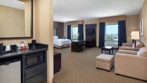 Une chambre d’hôtel comprenant un lit, un bureau, une kitchenette et un coin salon.
