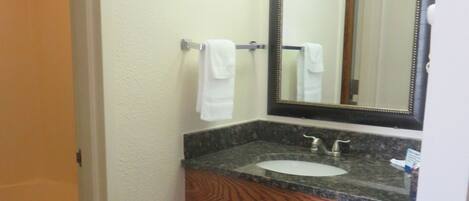 A bathroom with a sink, mirror, and towel rack.