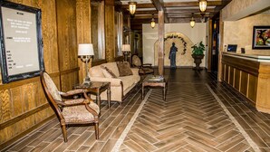 A lobby with wooden paneling, a sofa, chairs, a table, and a reception desk. - Baymont by Wyndham Fargo (Fargo)
