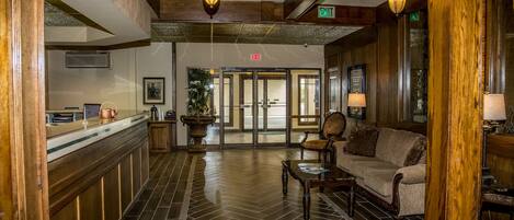 A lobby with a reception desk, a sofa, a coffee table, and a large potted plant.