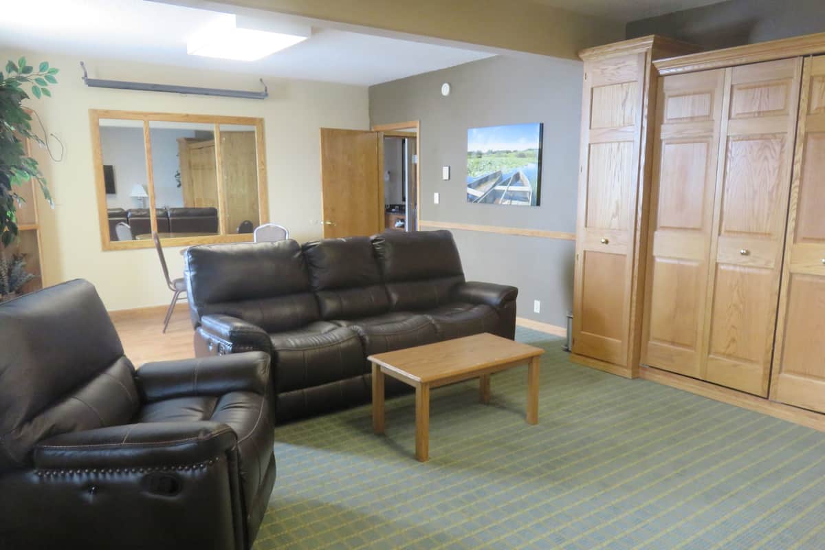 A living room with a leather sofa, a wooden coffee table, and a large wooden wardrobe.