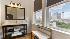 A bathroom with a large mirror, vanity, and a window with a city view. - Hotel Gibbs Downtown Riverwalk (San Antonio)