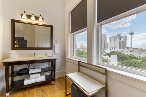 A bathroom with a large mirror, vanity, and a window with a city view.