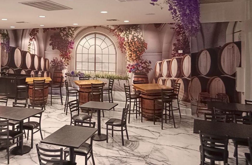A restaurant with marble flooring, wooden tables and chairs, and wine barrels.